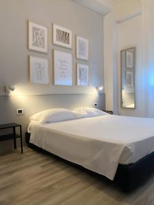 1 dormitorio con 1 cama blanca grande con cuadros en la pared en Il Romito, en Quercianella