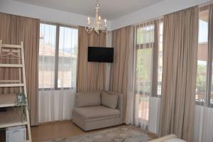 uma sala de estar com uma cadeira, uma televisão e janelas em Princess Apartment em Sandanski