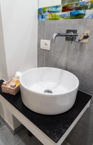 een witte wastafel op een zwart aanrecht in een badkamer bij Damè - Accommodation Amalfi Coast in Maiori