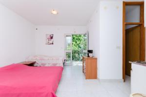 a bedroom with a pink bed and a balcony at Apartments Massimo in Rovinj