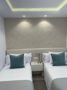 2 camas en una habitación de hotel con almohadas blancas y azules en Amarella Suite, en Marbella