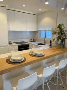 una cocina con armarios blancos y una barra de madera con sillas blancas. en Amarella Suite, en Marbella