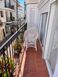 Un balcón con una silla blanca y una mesa. en Amarella Suite, en Marbella