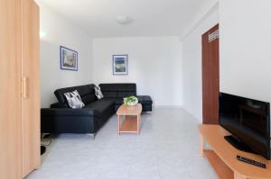 uma sala de estar com um sofá preto e uma mesa em Apartments Gloria em Vrsar