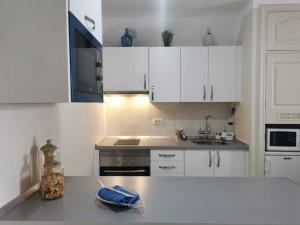 Una cocina con gabinetes blancos y encimera. en Rocas del Mar Apartment, en Costa del Silencio