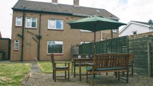 mesa y 2 sillas con sombrilla en Dwellcome Home Ltd 3 Bedroom Boldon House - see our site for assurance, en Boldon