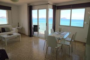 a living room with a table and chairs and the ocean at Hawaii Beach Can Picafort in Can Picafort