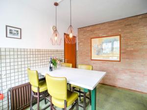 une salle à manger avec une table blanche et des chaises jaunes dans l'établissement Holiday home near the Efteling with garden, à Nieuwkuijk