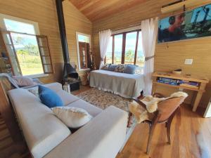 uma sala de estar com um sofá e uma cama em Cabana Pôr-do-Sol - Rancho Queimado/SC em Rancho Queimado