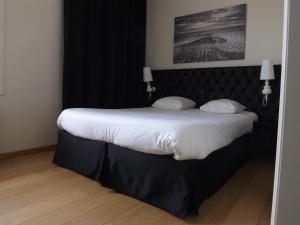 a bedroom with a large bed with a black headboard at Hotel Le Parisien in Ostend