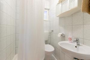 a white bathroom with a toilet and a sink at Apartments Ivan in Lopar