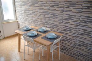 a wooden table and chairs in a room with a brick wall at Casa Vitorino in Sagres