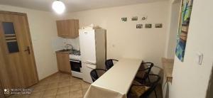 a kitchen with a white refrigerator and a table at Domek w Ćmińsku in Miedziana Góra