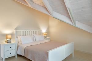 a bedroom with a white bed and two night stands at De Bosset Apartment 1 in Argostoli