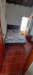 Cama en habitación con suelo de baldosa roja en Posada San Luis, en Páramo