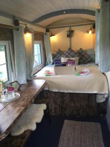 a room with two beds and a wooden table at Belan Bluebell Woods Shepherds Hut in Llanidloes