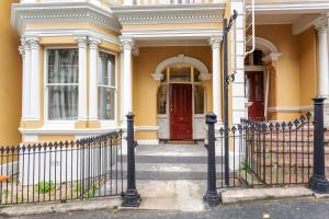 但尼丁的住宿－Character on Stuart St，黄色的房子,有红色的门和栅栏