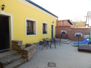 a yellow house with a patio with tables and chairs at Boros Vendégház II. in Kőszeg