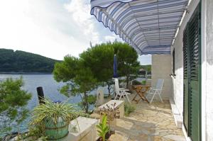 een patio met een tafel en stoelen en uitzicht op het water bij Beachfront Apartment in Tri Porte, with sea view, terrace, air conditioning, WiFi 5208-2 in Potirna