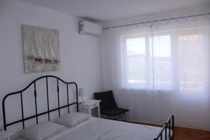 a bedroom with a bed and a chair and a window at SOLEIL - Newly renovated apartment close to the sea in Barbat na Rabu