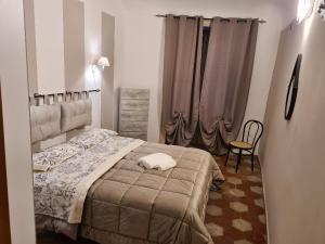 una camera con letto, sedia e tende di Agorà Sant’anna Apartment a Palermo