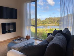 uma sala de estar com um sofá e uma grande janela em Messmates Luxury Eco Suites em Inverloch