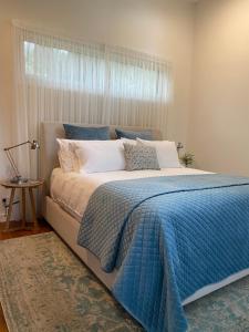 uma cama com um cobertor azul e uma janela em Messmates Luxury Eco Suites em Inverloch