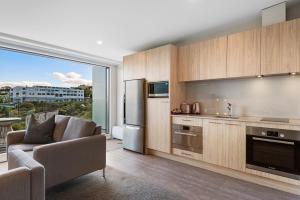 a kitchen with a couch and a chair in a room at FERNZ Motel & Apartments Birkenhead in Auckland