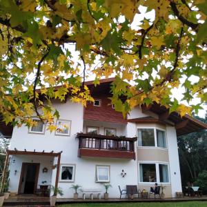 een wit huis met een balkon en herfstbladeren bij Villa Gruntal Hospedaria in Treze Tílias