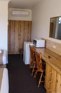 a room with a table and a microwave and a refrigerator at Motel Riverina in Leeton