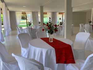 a room with white tables and white chairs and a vase with flowers at Aconchego Sertanejo in Caetité
