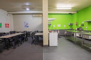 une salle de classe avec des tables, des chaises et des murs verts dans l'établissement Rock Solid Backpackers Rotorua, à Rotorua