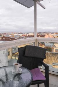 una mesa y una silla con una taza de café en el balcón en Mansarda, en San Petersburgo