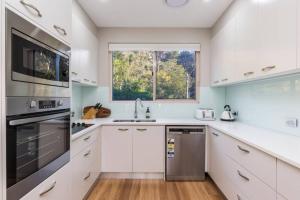 a kitchen with white cabinets and a window at Luxe at Brooklyn - Hawkesbury River Marina in Brooklyn