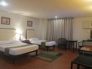 タクロバンにあるHotel Alejandro Taclobanのベッド2台とテーブルがあるホテルの部屋