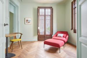 een woonkamer met een rode stoel en een tafel bij Le Palacete powered by Sonder in Barcelona