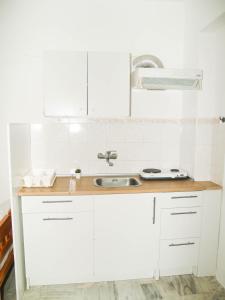 a kitchen with white cabinets and a sink at Lazaris Apartments in Agios Ioannis Lefkada in Lefkada Town