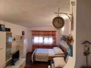 ein Schlafzimmer mit einem Bett und einer Uhr an der Wand in der Unterkunft Apartman Ella in Vrsi