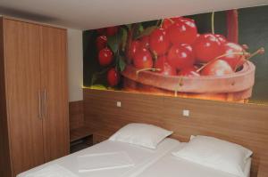 ein Schlafzimmer mit einem Gemälde einer Schüssel Kirschen in der Unterkunft Guest House Ostojić in Međugorje