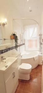 La salle de bains est pourvue de toilettes, d'une baignoire et d'un lavabo. dans l'établissement Fernhurst holiday apartments, à Shanklin