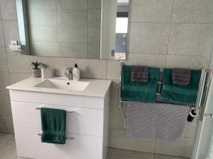 a bathroom with a sink and green towels at Mason lane Apartment in Whangarei