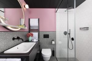 uma casa de banho rosa com um lavatório e um chuveiro em Alice Hotel em Budapeste