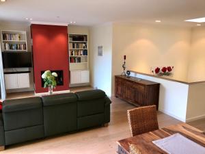 a living room with a couch and a red wall at Ferienhaus am Park am Röhrensee in Bayreuth