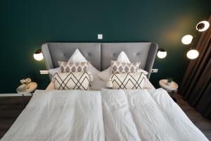 1 dormitorio con 1 cama con sábanas y almohadas blancas en Moselweingut & Gästehaus Hubertushof en Trittenheim