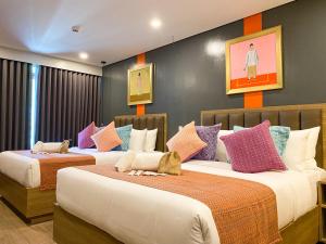 a bedroom with two beds with colorful pillows at UNWND Flats in Manila