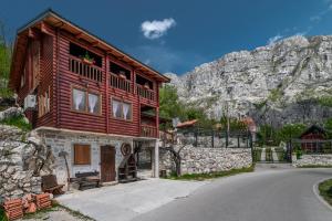 a large wooden house with a mountain in the background at Holiday Village Ostrog in Nikšić