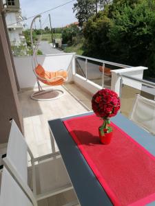 a balcony with a red table with a chair and a flower at Crystal Blue Apartments in Nea Kalikratia