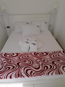 a white bed with a red and white blanket on it at Crystal Blue Apartments in Nea Kalikratia