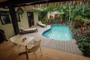 uma banheira de hidromassagem num deque com uma mesa e cadeiras em Rendezvous Villas em Rarotonga
