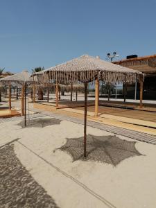 a group of straw umbrellas on a beach at Crystal Blue Apartments in Nea Kalikratia